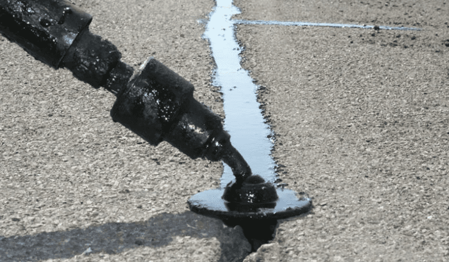 Hot asphalt crack filler being applied to a parking lot